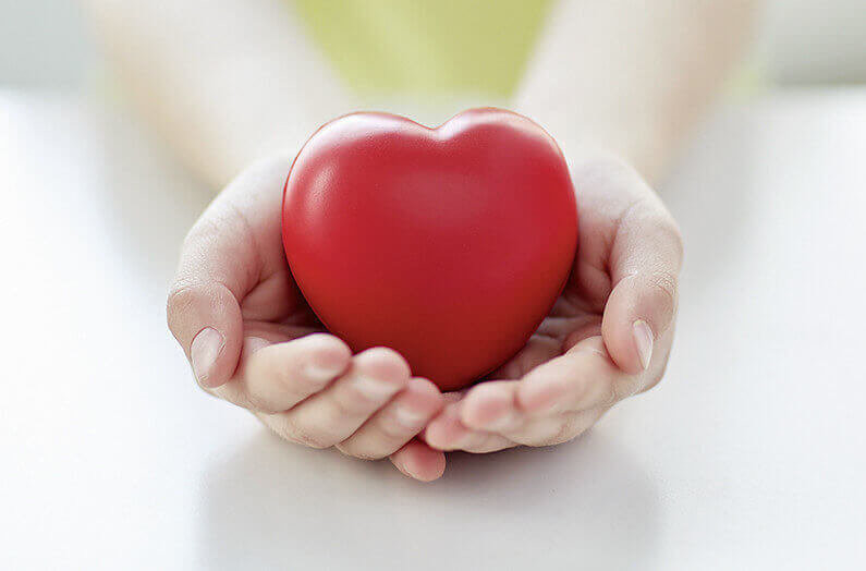 people, love, charity and family concept - close up of child hands holding red heart shape at home
