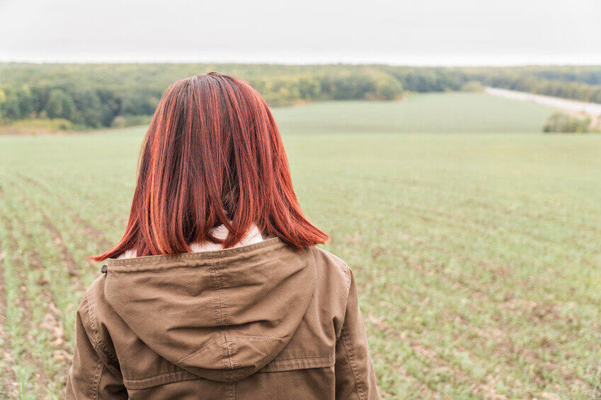 Portrait of a woman agronomist looking at the field, rear view
