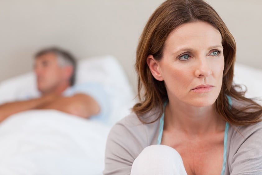 traurige Frau im Bett mit ihrem Mann im Hintergrund