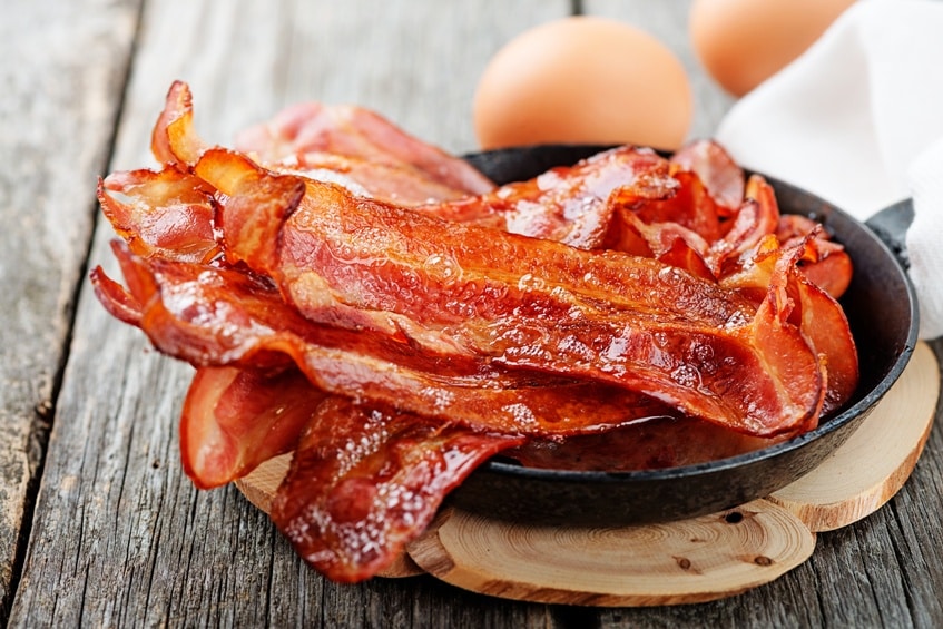 Hot fried bacon pieces in a cast iron skillet.top view