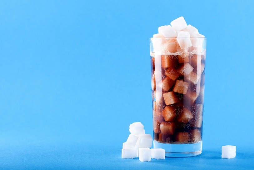Glas Cola mit vielen Zuckerwürfeln drin