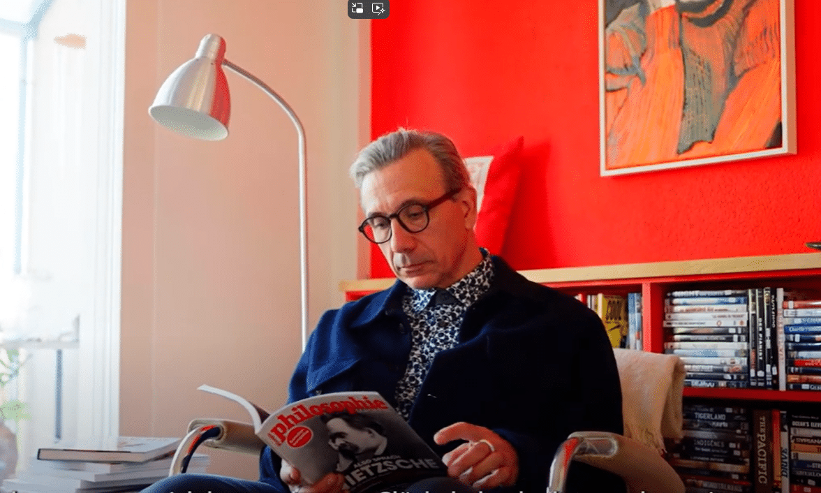 Mann sitzt im Wohnzimmer und liest ein Magazin