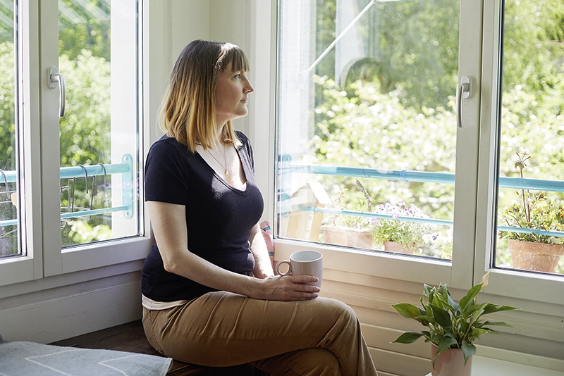 Frau mit Long Covid sitzt im Wohnzimmer