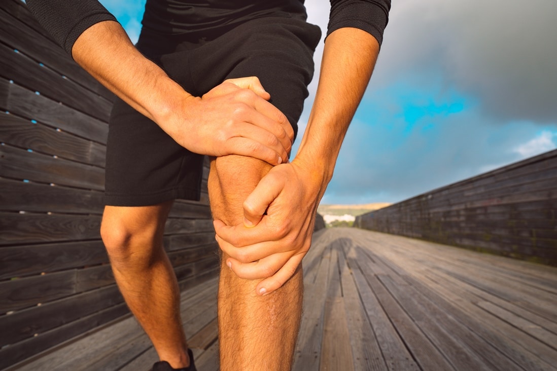 Mann hält sein Knie wegen Knieschmerzen