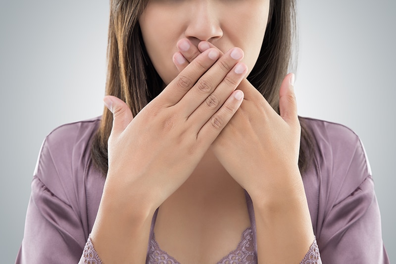 Asian woman in purple nightgown use both hands close mouth for Not commenting or refusing against gray background