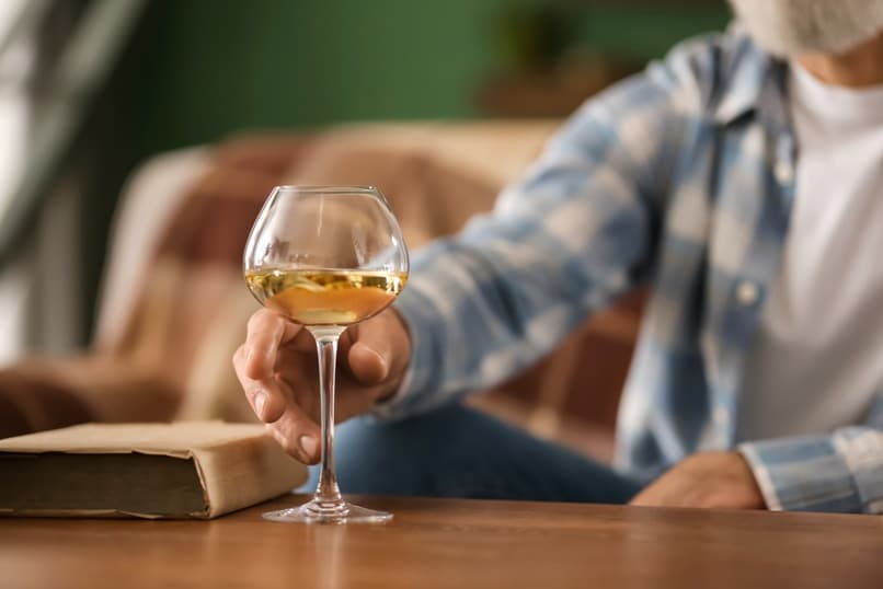 Ein älterer Herr nimmt ein Glas Wein von einem Tisch