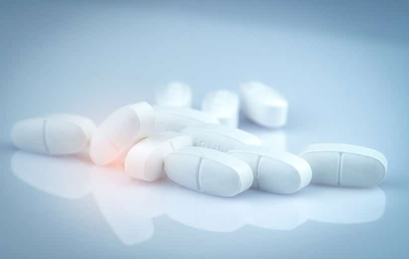 Pile of white oblong tablets pills on gradient background. Pharmaceutical industry. Pharmacy product. Global healthcare. Drug in pharmacy drugstore or hospital. Drug use in pregnancy and lactation.