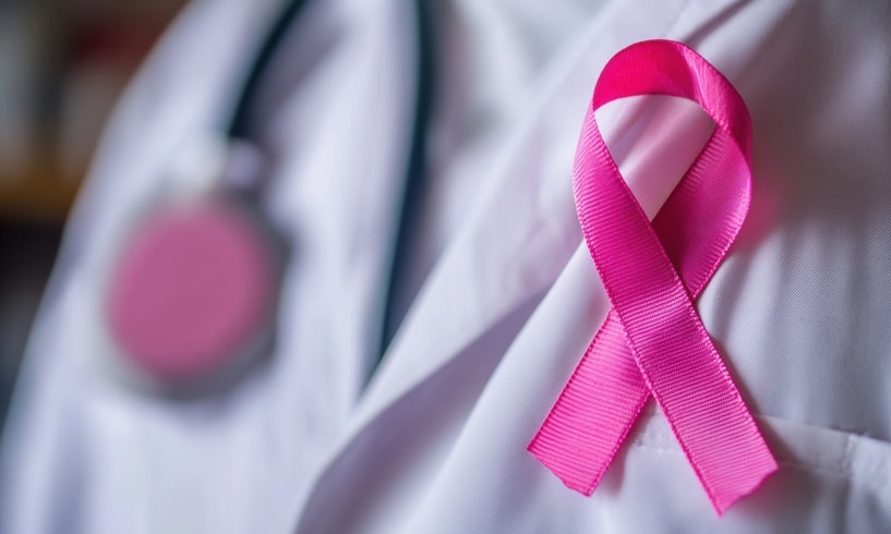 Pink ribbon pinned to a doctors lab coat in recognition of breast cancer awareness