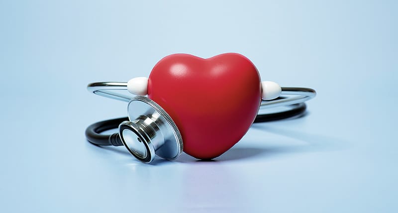 Red heart shape exercise ball with doctor physician's stethoscope on blue background, hospital life insurance concept, world heart health day. doctor day