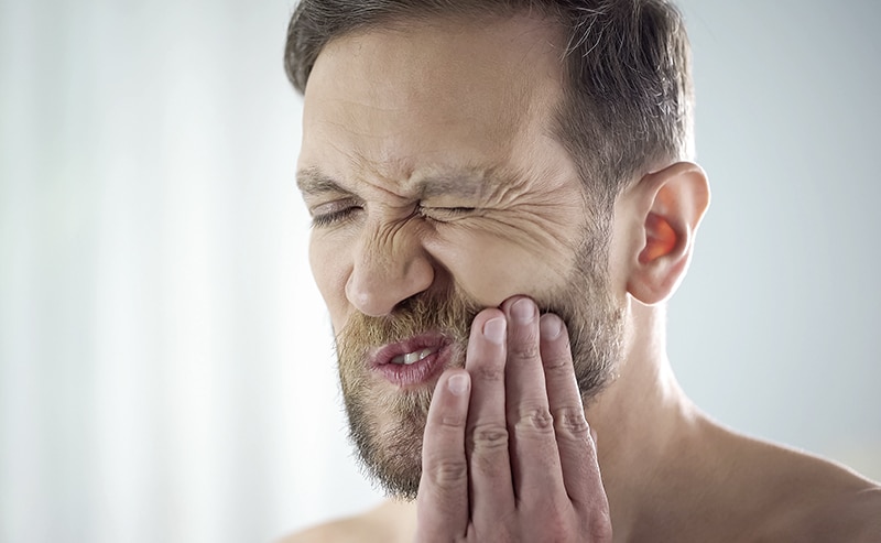 Male suffering from tooth ache, strong dental pain, pulp inflammation, decay