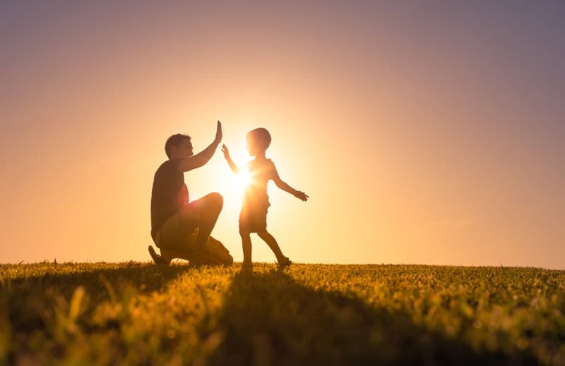 Happy father playing with his son giving him a high five. Father son relationship concept