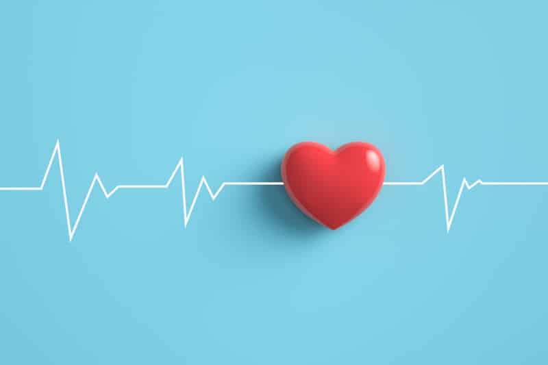 Cardiogram pulse trace with Red heart on pastel blue background.