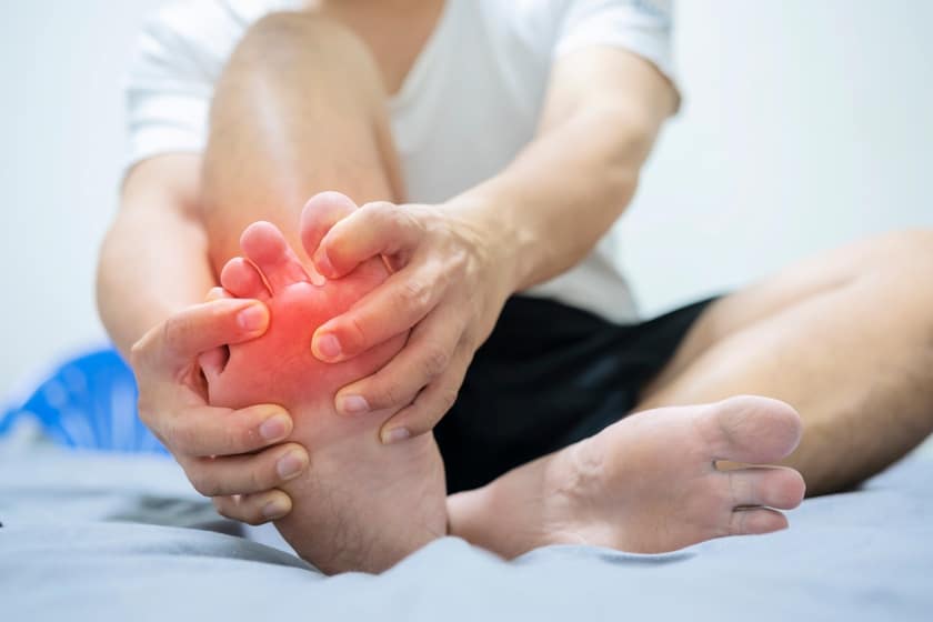 Man on bed with pillow embrace foot with painful swollen gout inflammation